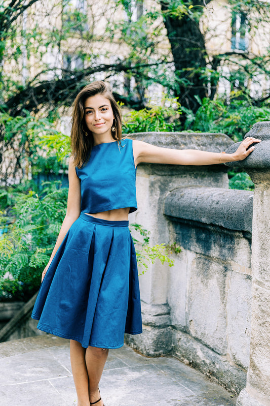 Ensemble 'Lucile' avec jupe à plis et crop-top sans manches en piqué de coton bleu, porté par un modèle, vue complète. 